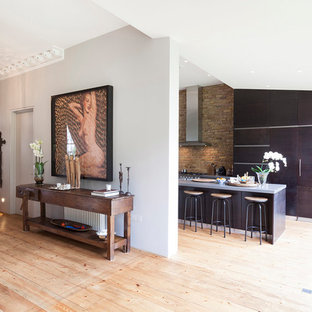 Design ideas for a large contemporary galley eat-in kitchen in London with flat-panel cabinets, dark wood cabinets, limestone benchtops and with island.