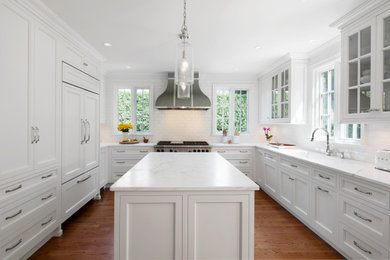 Kitchen - large transitional u-shaped brown floor and medium tone wood floor kitchen idea in New York with a single-bowl sink, recessed-panel cabinets, white cabinets, marble countertops, white backsplash, subway tile backsplash, paneled appliances, an island and white countertops