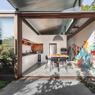 Inspiration for a contemporary l-shaped eat-in kitchen in Sydney with flat-panel cabinets, white cabinets, brown splashback, timber splashback, concrete floors, no island and grey floor.
