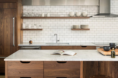 Example of a transitional medium tone wood floor kitchen design in Portland Maine with an undermount sink, dark wood cabinets, marble countertops, white backsplash, ceramic backsplash, paneled appliances and an island