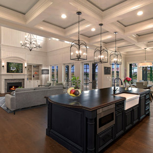 Inspiration for a timeless medium tone wood floor and brown floor open concept kitchen remodel in Jacksonville with a farmhouse sink, raised-panel cabinets, blue cabinets, black appliances, an island and brown countertops