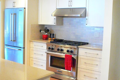 Example of a mid-sized trendy u-shaped medium tone wood floor enclosed kitchen design in San Francisco with an undermount sink, shaker cabinets, white cabinets, quartz countertops, white backsplash, ceramic backsplash, stainless steel appliances and no island