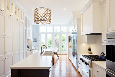 Diseño de cocina actual con puertas de armario blancas, salpicadero blanco y electrodomésticos de acero inoxidable