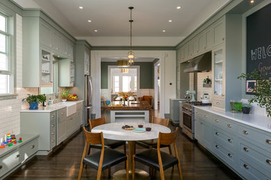 Inspiration for a victorian enclosed kitchen in San Francisco with a belfast sink, shaker cabinets, white splashback, metro tiled splashback, stainless steel appliances, dark hardwood flooring, an island and green cabinets.