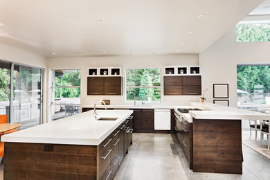Example of a mid-sized minimalist l-shaped concrete floor and gray floor open concept kitchen design in Los Angeles with an undermount sink, flat-panel cabinets, dark wood cabinets, solid surface countertops, white appliances, an island and white countertops