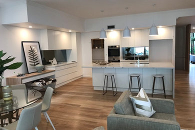 Zweizeilige, Große Moderne Küche mit Granit-Arbeitsplatte, Küchenrückwand in Schwarz, Glasrückwand, Küchengeräten aus Edelstahl und hellem Holzboden in Brisbane