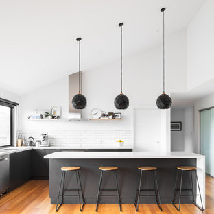 This is an example of a contemporary l-shaped kitchen in Hobart with an undermount sink, flat-panel cabinets, grey cabinets, white splashback, subway tile splashback, stainless steel appliances, medium hardwood floors, with island, brown floor and white benchtop.