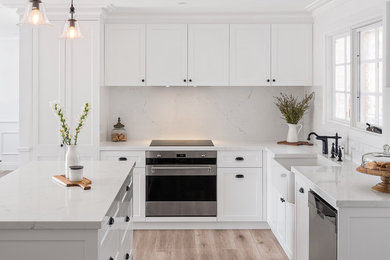 Idéer för att renovera ett mellanstort vintage vit vitt kök, med en rustik diskho, skåp i shakerstil, vita skåp, marmorbänkskiva, vitt stänkskydd, stänkskydd i marmor, rostfria vitvaror, laminatgolv, en köksö och brunt golv