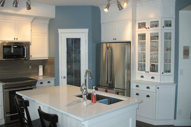 Example of a transitional dark wood floor eat-in kitchen design in Calgary with an undermount sink, white cabinets, stainless steel appliances, an island, shaker cabinets, granite countertops, beige backsplash and ceramic backsplash