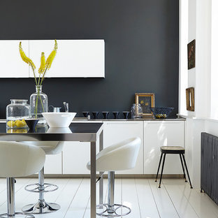 Contemporary kitchen in Belfast with flat-panel cabinets, white cabinets, black splashback, an island and white floors.