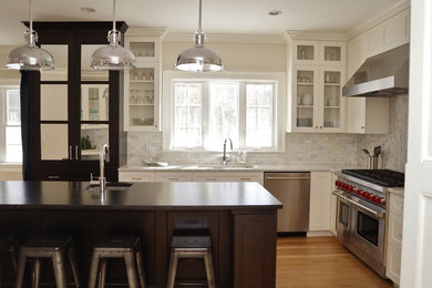 Inspiration for a mid-sized industrial l-shaped light wood floor and brown floor eat-in kitchen remodel in Boston with an undermount sink, white cabinets, gray backsplash, stainless steel appliances, an island, subway tile backsplash, shaker cabinets, laminate countertops and white countertops