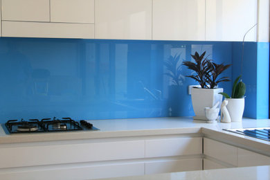 Diseño de cocina comedor actual con salpicadero azul y salpicadero de vidrio templado