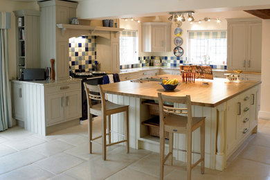 Photo of a farmhouse l-shaped kitchen in Other with shaker cabinets, granite worktops, an island, multi-coloured splashback, mosaic tiled splashback and black appliances.
