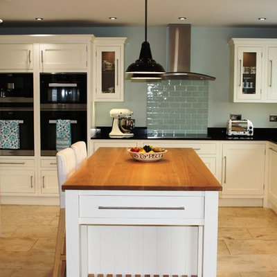 Eat-in kitchen - mid-sized traditional u-shaped travertine floor eat-in kitchen idea in West Midlands with an undermount sink, shaker cabinets, white cabinets, granite countertops, green backsplash, ceramic backsplash, an island and black appliances