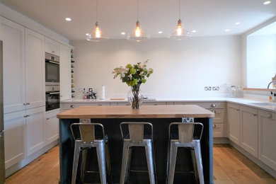Immagine di una grande cucina design con ante in stile shaker, ante grigie, top in quarzite, elettrodomestici da incasso e pavimento in legno massello medio