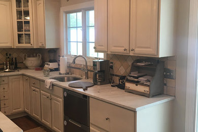 Inspiration for a mid-sized timeless l-shaped medium tone wood floor and brown floor kitchen remodel in New York with an undermount sink, raised-panel cabinets, white cabinets, marble countertops, beige backsplash, cement tile backsplash, stainless steel appliances and an island