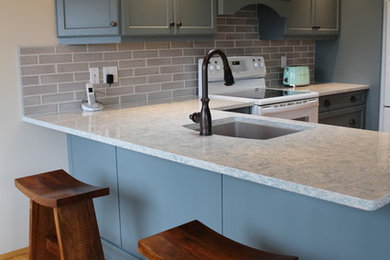 Elegant kitchen photo in Vancouver with blue cabinets, quartz countertops, gray backsplash and ceramic backsplash