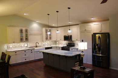 Inspiration for a large farmhouse u-shaped dark wood floor and brown floor eat-in kitchen remodel in Other with a farmhouse sink, recessed-panel cabinets, white cabinets, marble countertops, gray backsplash, ceramic backsplash, black appliances and an island
