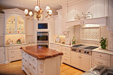 Inspiration for a mid-sized timeless u-shaped light wood floor and brown floor enclosed kitchen remodel in Boston with a double-bowl sink, raised-panel cabinets, white cabinets, granite countertops, white backsplash, porcelain backsplash, stainless steel appliances and an island