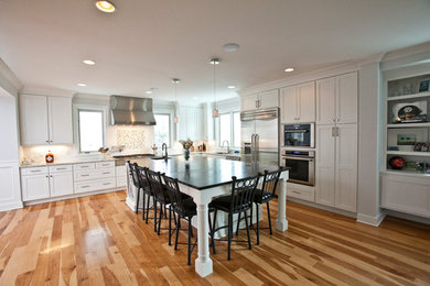 Large transitional l-shaped light wood floor and beige floor open concept kitchen photo in Cincinnati with an undermount sink, shaker cabinets, white cabinets, solid surface countertops, multicolored backsplash, glass tile backsplash, stainless steel appliances, an island and black countertops