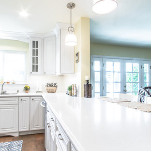 Photo of a mid-sized shabby-chic style u-shaped eat-in kitchen in Orange County with an undermount sink, raised-panel cabinets, white cabinets, quartz benchtops, white splashback, ceramic splashback, stainless steel appliances and porcelain floors.