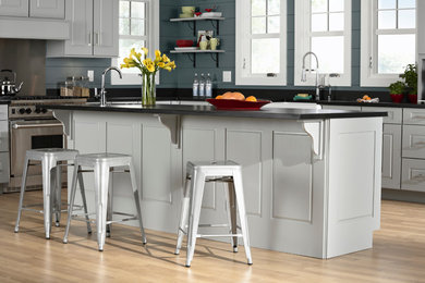 Eat-in kitchen - mid-sized traditional l-shaped light wood floor eat-in kitchen idea in Denver with a double-bowl sink, raised-panel cabinets, white cabinets, quartz countertops, stainless steel appliances and an island
