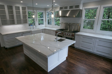 Example of a classic dark wood floor and brown floor eat-in kitchen design in Portland with a farmhouse sink, shaker cabinets, white cabinets, quartz countertops, white backsplash, subway tile backsplash, stainless steel appliances, an island and white countertops