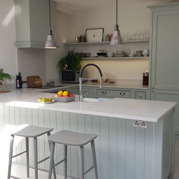 Pale green, traditional kitchen with breakfast bar, white worktops and chrome fi