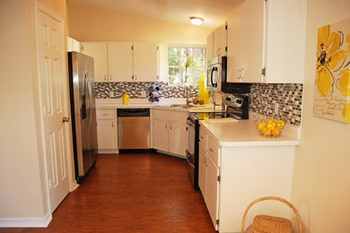 Inspiration for a small transitional galley medium tone wood floor enclosed kitchen remodel in Orlando with a drop-in sink, flat-panel cabinets, white cabinets, laminate countertops, metallic backsplash, glass tile backsplash and stainless steel appliances