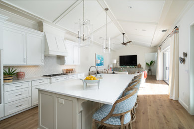 Inspiration for a large coastal l-shaped light wood floor and beige floor open concept kitchen remodel in Other with an undermount sink, shaker cabinets, white cabinets, quartz countertops, beige backsplash, marble backsplash, paneled appliances, an island and white countertops
