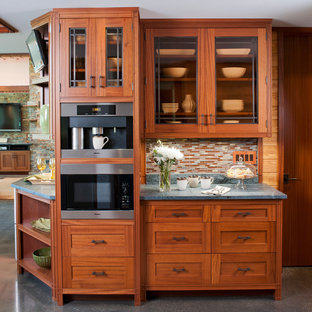 Aménagement d'une grand cuisine ouverte craftsman en U avec un évier posé, un placard avec porte à panneau encastré, des portes de placard en bois brun, un plan de travail en stéatite, une crédence multicolore, une crédence en mosaïque, un électroménager blanc, béton au sol, 2 îlots et un sol gris.