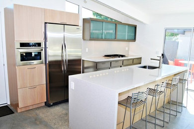 Mid-sized 1960s l-shaped concrete floor eat-in kitchen photo in Los Angeles with an undermount sink, flat-panel cabinets, medium tone wood cabinets, quartz countertops, yellow backsplash, white appliances and two islands
