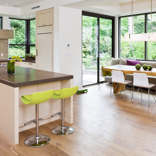 Ispirazione per una grande cucina design con elettrodomestici in acciaio inossidabile, ante lisce, ante bianche, top in quarzo composito, lavello sottopiano, pavimento in legno massello medio, paraspruzzi beige, paraspruzzi con piastrelle di vetro, isola, pavimento marrone e top marrone