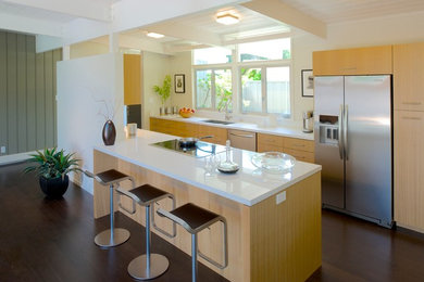 Open concept kitchen - mid-sized 1950s single-wall laminate floor open concept kitchen idea in San Francisco with a double-bowl sink, flat-panel cabinets, light wood cabinets, quartz countertops, white backsplash, stone slab backsplash, stainless steel appliances and an island