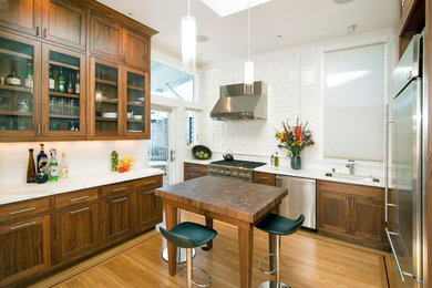Kitchen - mid-sized contemporary u-shaped light wood floor and beige floor kitchen idea in San Francisco with an undermount sink, glass-front cabinets, medium tone wood cabinets, quartz countertops, white backsplash, stainless steel appliances, an island and white countertops