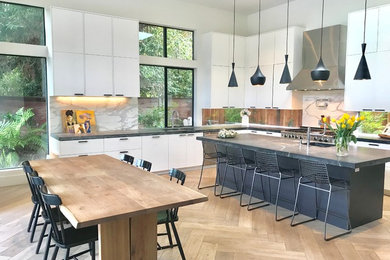 Trendy l-shaped light wood floor and beige floor eat-in kitchen photo in San Francisco with flat-panel cabinets, white cabinets, an island and gray countertops