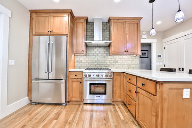 Example of a mid-sized transitional medium tone wood floor and brown floor enclosed kitchen design in San Francisco with an undermount sink, shaker cabinets, medium tone wood cabinets, quartz countertops, subway tile backsplash, stainless steel appliances and white countertops