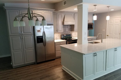Large trendy single-wall light wood floor and gray floor eat-in kitchen photo in DC Metro with an undermount sink, recessed-panel cabinets, gray cabinets, quartz countertops, gray backsplash, ceramic backsplash, stainless steel appliances and an island