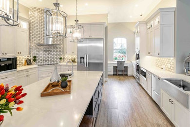 Inspiration for a huge transitional porcelain tile and beige floor eat-in kitchen remodel in Tampa with a farmhouse sink, shaker cabinets, white cabinets, quartz countertops, white backsplash, stone tile backsplash, stainless steel appliances, an island and white countertops