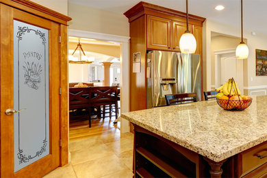 Example of a mid-sized arts and crafts l-shaped kitchen pantry design in Other with raised-panel cabinets, medium tone wood cabinets, granite countertops, beige backsplash, ceramic backsplash, stainless steel appliances and an island