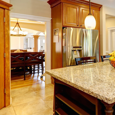 Mid-sized arts and crafts l-shaped kitchen pantry photo in Other with raised-panel cabinets, medium tone wood cabinets, granite countertops, beige backsplash, ceramic backsplash, stainless steel appliances and an island