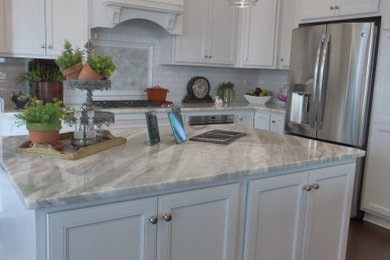 Example of a mid-sized transitional u-shaped enclosed kitchen design in Richmond with a drop-in sink, beaded inset cabinets, white cabinets, white backsplash, ceramic backsplash, stainless steel appliances and an island