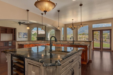 Eat-in kitchen - mid-sized traditional u-shaped dark wood floor eat-in kitchen idea in Albuquerque with an undermount sink, raised-panel cabinets, medium tone wood cabinets, marble countertops, multicolored backsplash, cement tile backsplash, paneled appliances and two islands