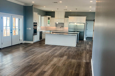 Example of a large classic single-wall vinyl floor and brown floor enclosed kitchen design in Orange County with shaker cabinets, white cabinets and two islands