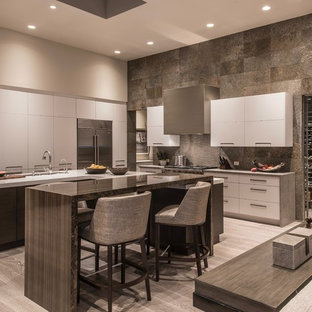 This is an example of an expansive contemporary u-shaped open plan kitchen in Phoenix with an undermount sink, flat-panel cabinets, white cabinets, quartz benchtops, slate splashback, stainless steel appliances, light hardwood floors, multiple islands, beige floor and grey benchtop.