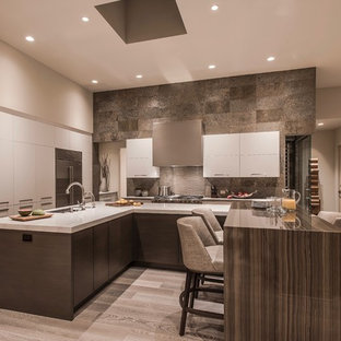 Design ideas for an expansive contemporary u-shaped open plan kitchen in Phoenix with an undermount sink, flat-panel cabinets, white cabinets, quartz benchtops, green splashback, slate splashback, stainless steel appliances, light hardwood floors, multiple islands, beige floor and white benchtop.