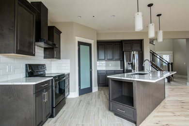 This is an example of a medium sized classic single-wall kitchen/diner in Calgary with a submerged sink, raised-panel cabinets, dark wood cabinets, marble worktops, white splashback, metro tiled splashback, stainless steel appliances, light hardwood flooring, an island, beige floors and white worktops.