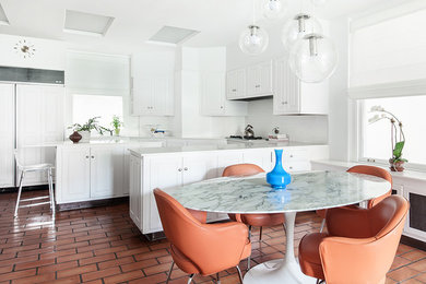 Example of a large minimalist l-shaped ceramic tile eat-in kitchen design in New York with raised-panel cabinets, white cabinets, marble countertops, white backsplash, ceramic backsplash, white appliances and an island