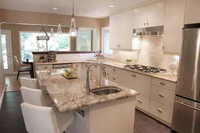 Example of a mid-sized transitional u-shaped porcelain tile and gray floor eat-in kitchen design in Vancouver with an undermount sink, flat-panel cabinets, white cabinets, granite countertops, beige backsplash, stone tile backsplash, stainless steel appliances and an island