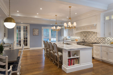Eat-in kitchen - traditional galley medium tone wood floor eat-in kitchen idea in New York with an undermount sink, shaker cabinets, white cabinets, gray backsplash, stainless steel appliances and an island
